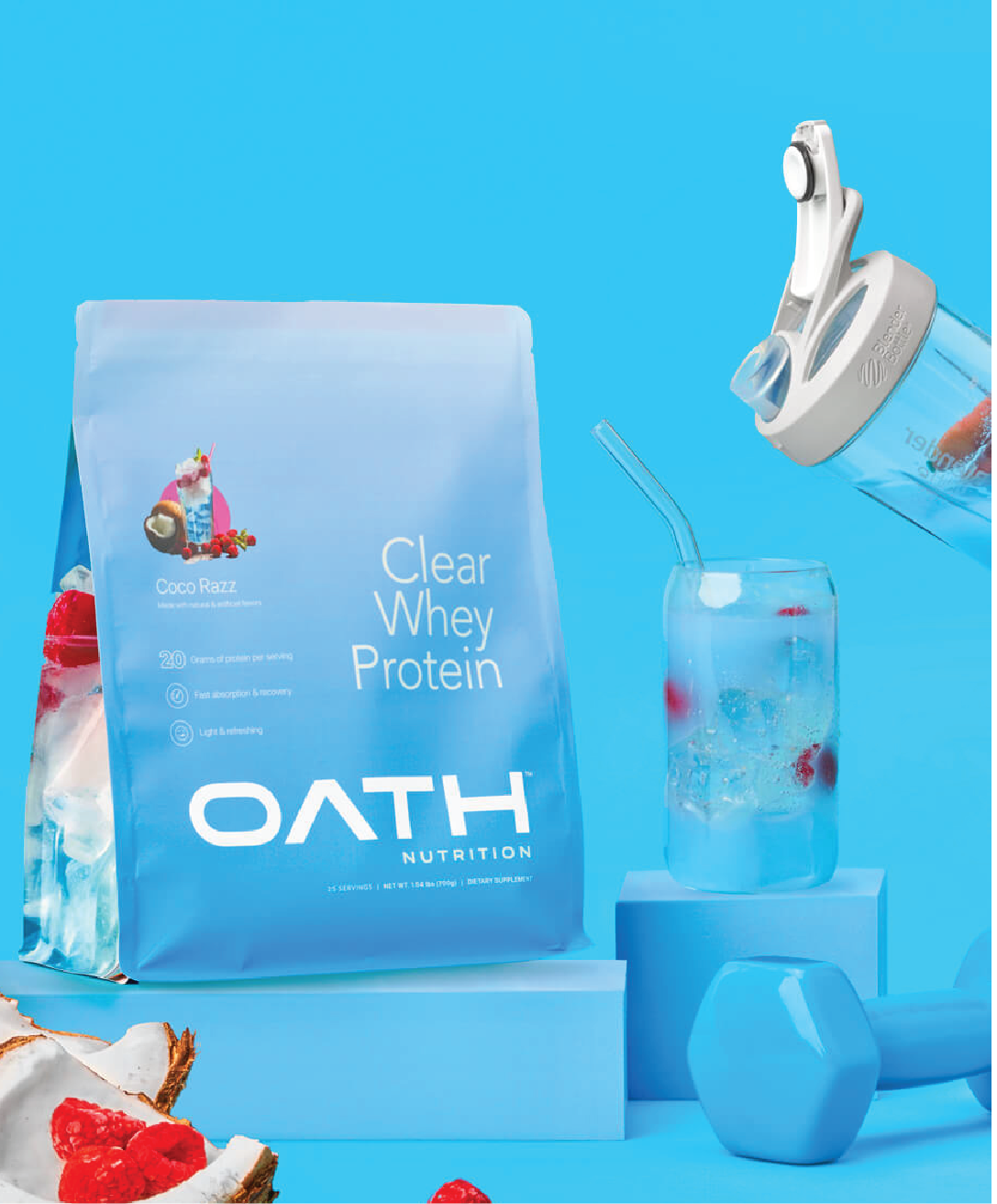 an image of Coco Razz flavor Oath Clear Whey Protein packaging surrounded by coconuts, raspberries, a blue dumbbell, and a glass of the drink with raspberries in it.