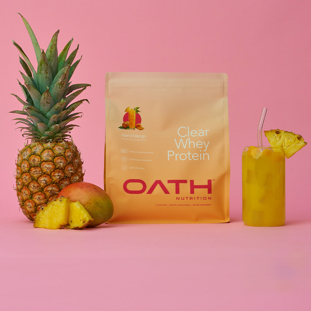 Oath Clear Whey protein bag next to a pineapple, mango, and glass full of delicious clear whey