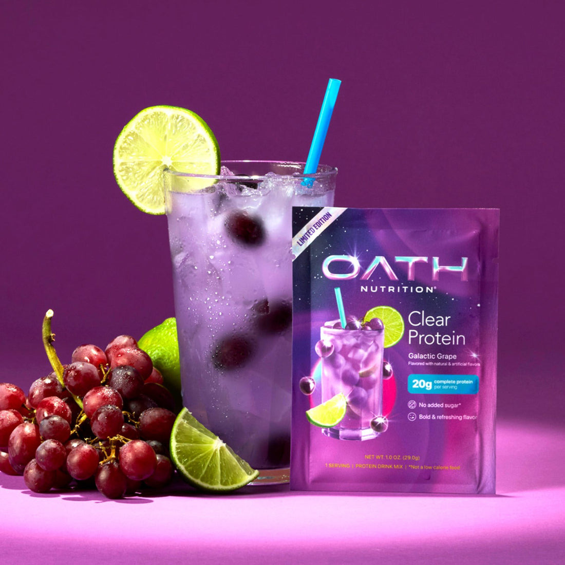 A packet of OATH Nutrition Clear Protein Galactic Grape flavor stands next to a glass of iced purple protein drink garnished with a lime slice and a blue straw, with red grapes and lime wedges.